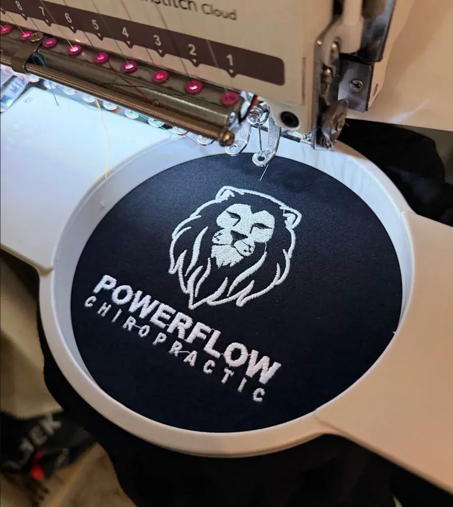 Powerflow Chiropractic lion logo embroidered in white on navy fabric