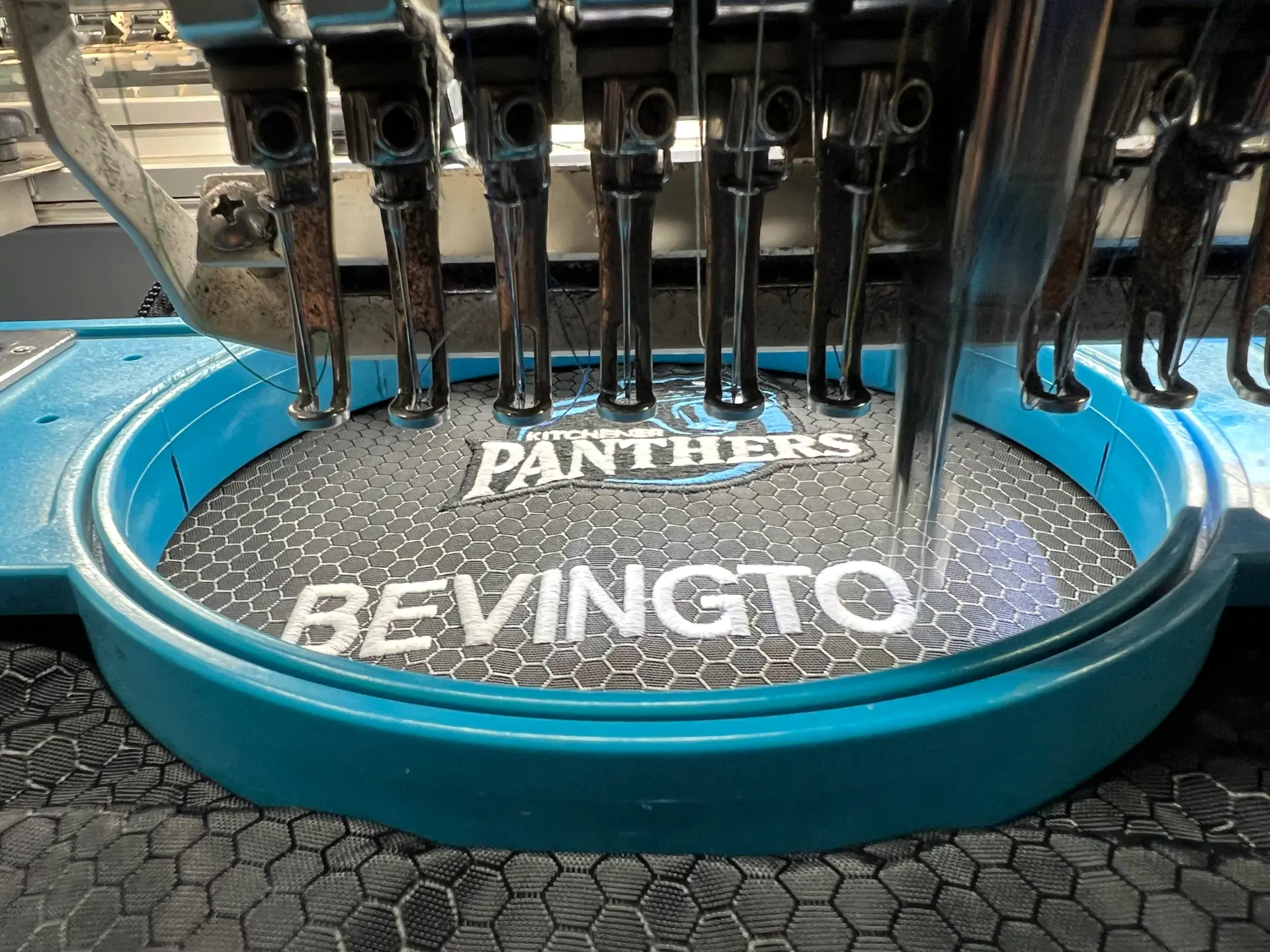 White business name embroidered on teal fabric
