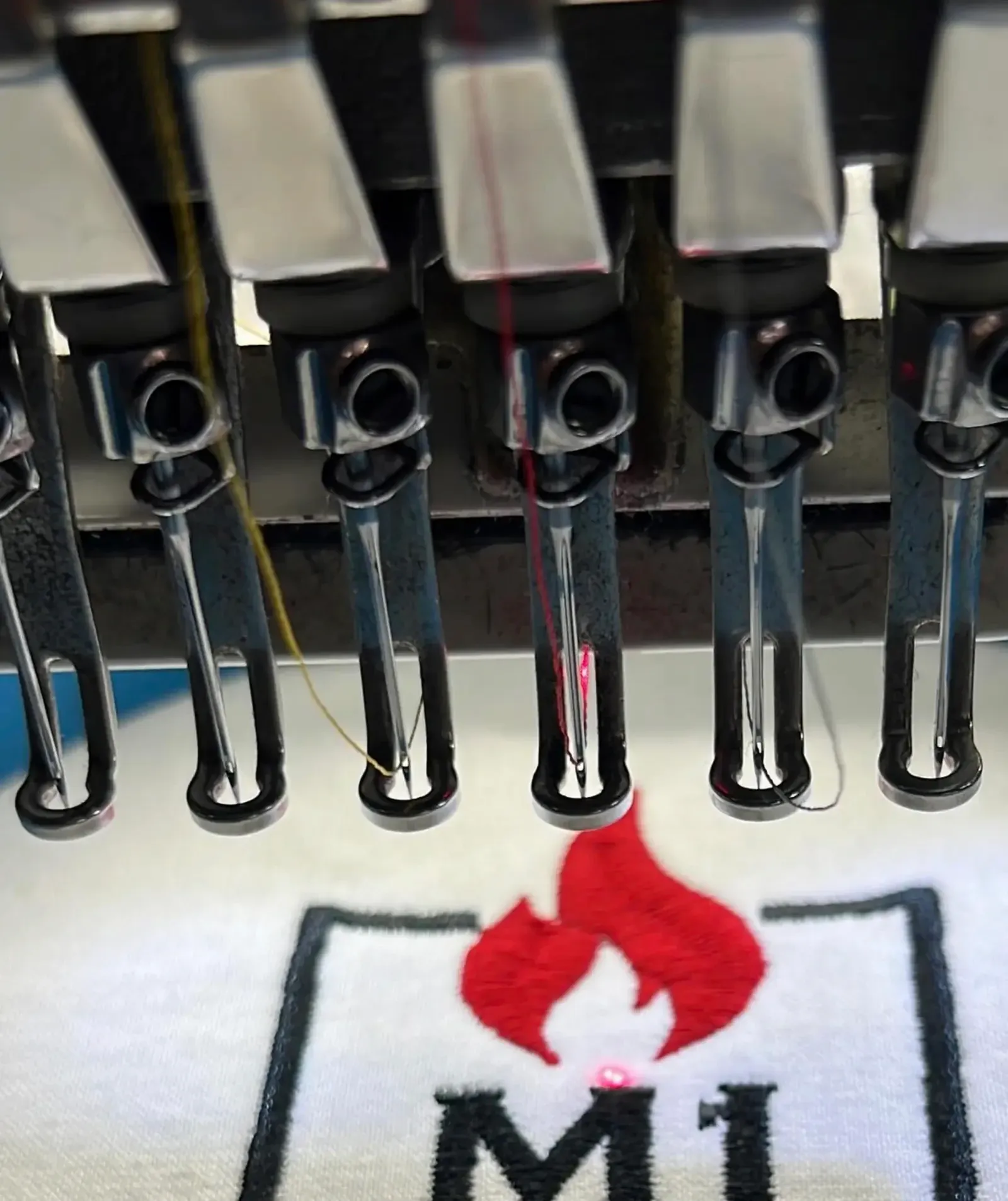 Multi-head embroidery machine stitching a red design