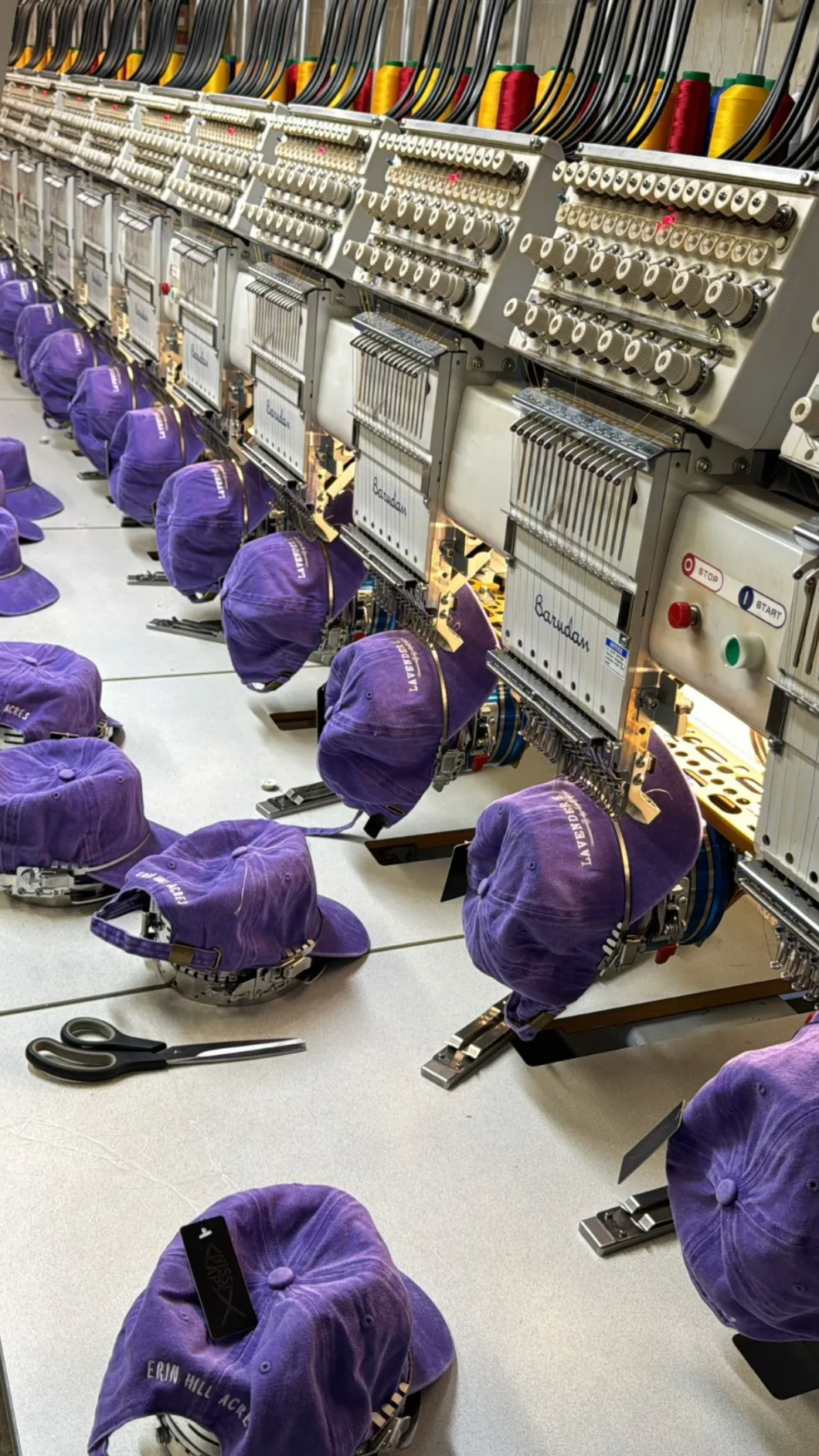 Multi-head embroidery machines stitching custom purple caps in production